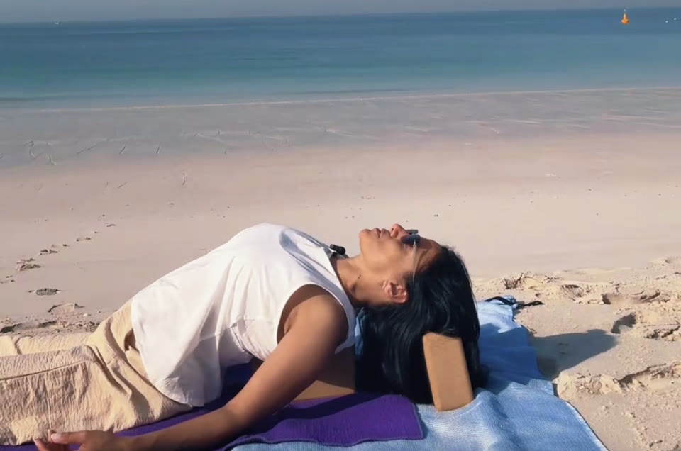 Supported backbend over a yoga block by the sea