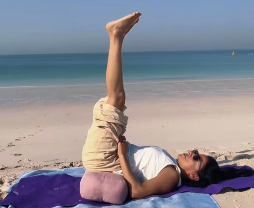 Legs raised over a bolster by the sea